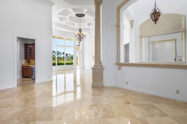 interior space featuring a high ceiling, a chandelier, baseboards, decorative columns, and coffered ceiling