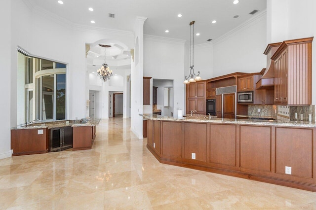kitchen featuring built in appliances, a high ceiling, a notable chandelier, and crown molding