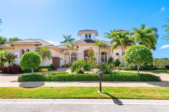 mediterranean / spanish-style house with an attached garage, driveway, and stucco siding