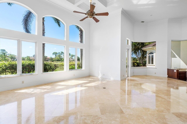 unfurnished living room featuring crown molding, a wealth of natural light, and a towering ceiling