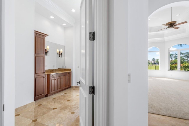 hallway featuring light colored carpet, arched walkways, a sink, ornamental molding, and recessed lighting