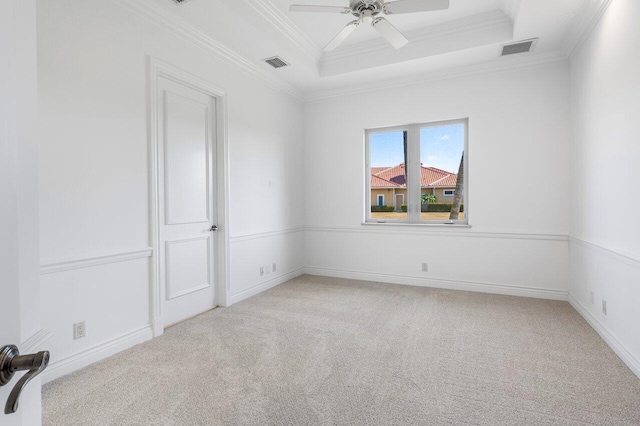 spare room with ceiling fan, ornamental molding, a tray ceiling, and visible vents