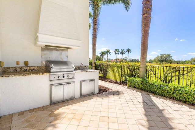view of patio / terrace featuring a sink, fence, an outdoor kitchen, and a grill