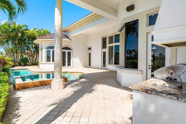 view of patio / terrace featuring an outdoor pool, french doors, and an outdoor kitchen