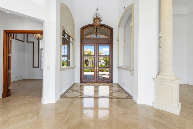 entrance foyer with baseboards, a notable chandelier, marble finish floor, and a towering ceiling