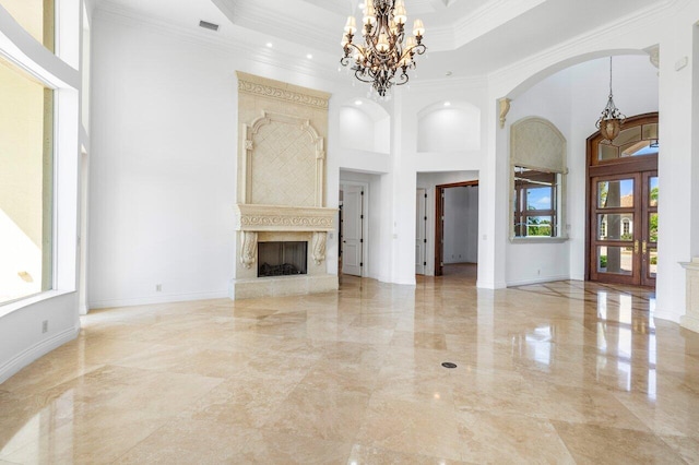 unfurnished living room with crown molding, arched walkways, a chandelier, marble finish floor, and a towering ceiling