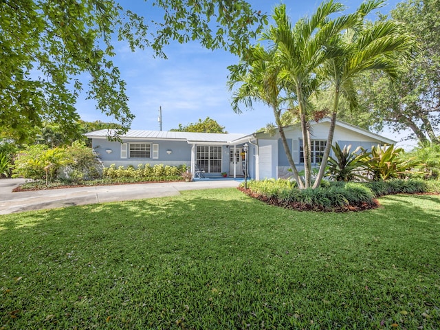 view of front of home with a garage, concrete driveway, metal roof, and a front yard
