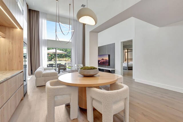 5607 NW 24th Ter, Boca Raton, FL 33496 - dining area featuring light wood-type flooring, a towering ceiling, and visible vents