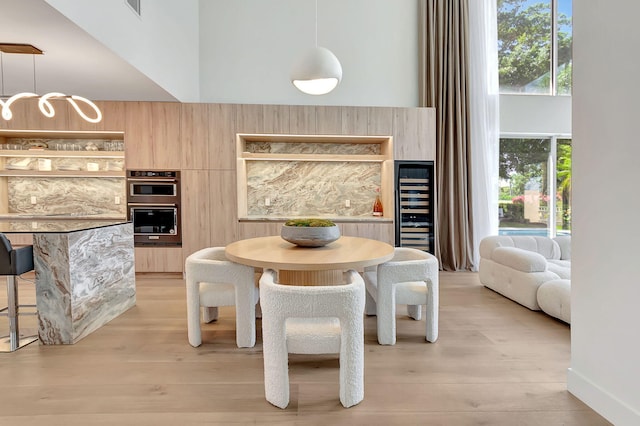 5607 NW 24th Ter, Boca Raton, FL 33496 - dining area with beverage cooler, light wood-style floors, a towering ceiling, and a chandelier