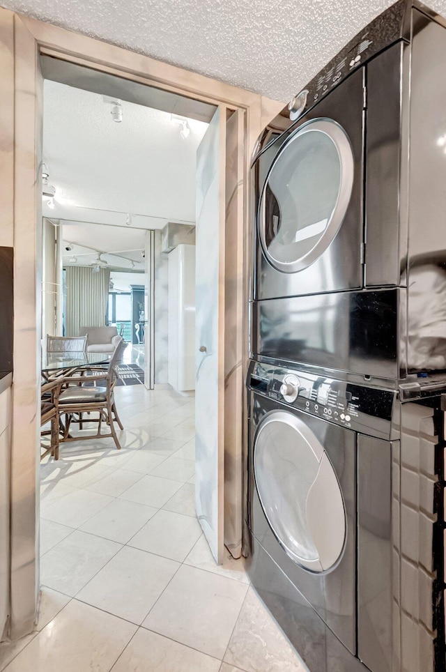 7578 Regency Lake Dr Unit 702, Boca Raton, FL 33433 - clothes washing area with laundry area, stacked washer and clothes dryer, a textured ceiling, and light tile patterned flooring