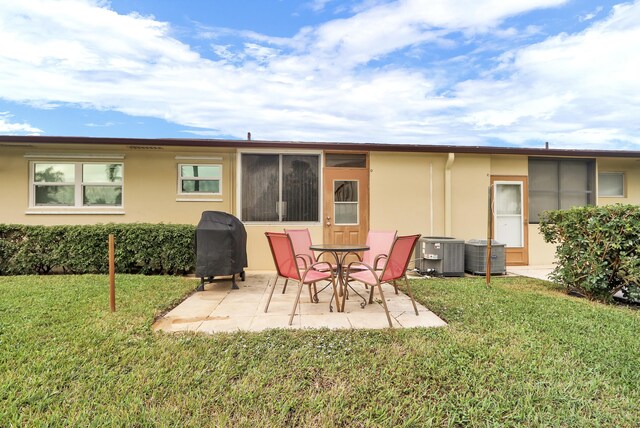 2852 W Crosley Dr W Unit D, West Palm Beach, FL 33415 - rear view of property featuring stucco siding, a patio, a lawn, and central AC unit