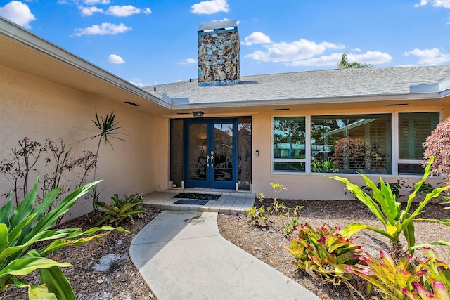 1256 Holly Cove Dr, Jupiter, FL 33458 - property entrance featuring french doors, stucco siding, a chimney, and roof with shingles