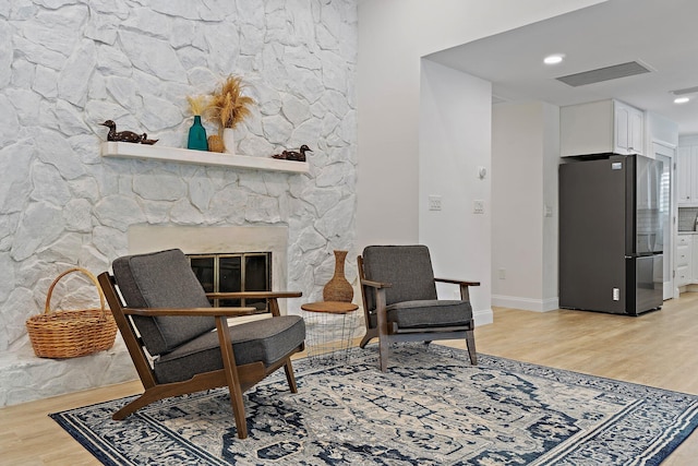 1256 Holly Cove Dr, Jupiter, FL 33458 - living area featuring baseboards, light wood-type flooring, a stone fireplace, and visible vents
