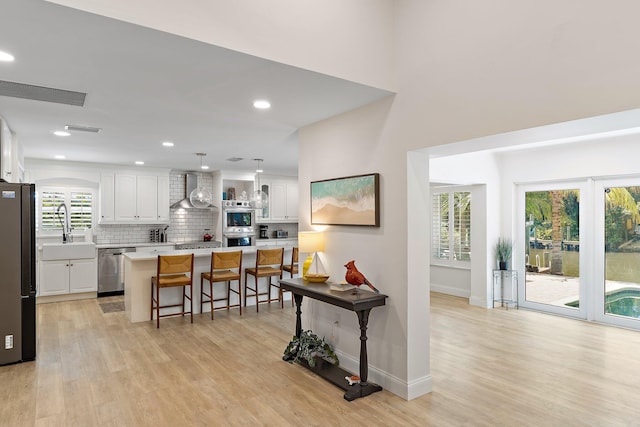 1256 Holly Cove Dr, Jupiter, FL 33458 - kitchen with wall chimney range hood, a kitchen bar, white cabinets, a sink, and stainless steel appliances