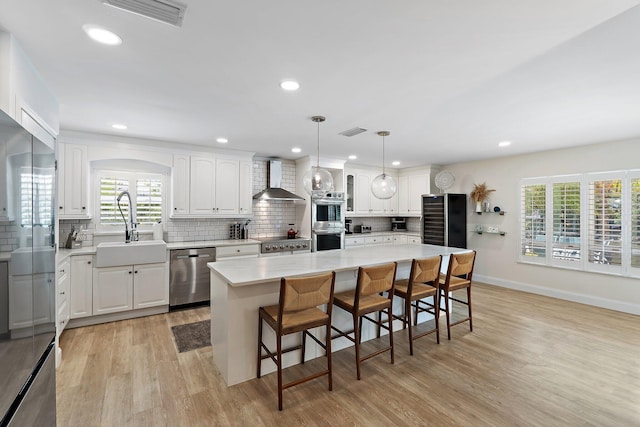 1256 Holly Cove Dr, Jupiter, FL 33458 - kitchen with appliances with stainless steel finishes, a sink, wall chimney exhaust hood, light wood-type flooring, and visible vents