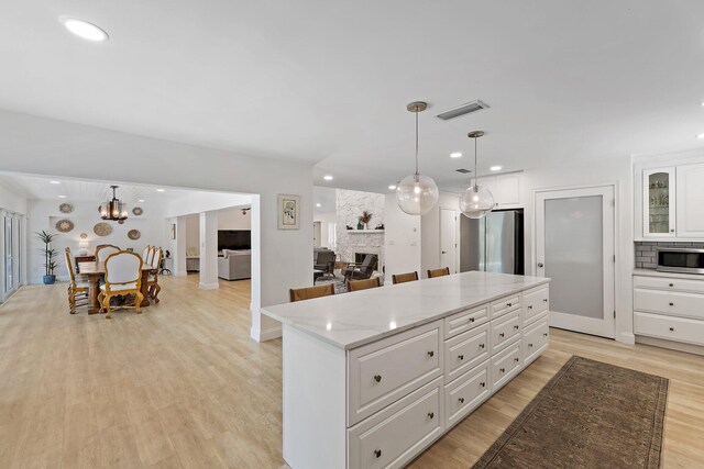 1256 Holly Cove Dr, Jupiter, FL 33458 - kitchen with white cabinets, light wood-style flooring, freestanding refrigerator, open floor plan, and a kitchen island
