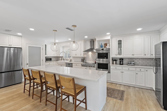 1256 Holly Cove Dr, Jupiter, FL 33458 - kitchen featuring visible vents, a breakfast bar area, wall chimney range hood, appliances with stainless steel finishes, and backsplash