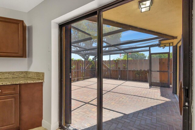 doorway featuring a sunroom, a wealth of natural light, and brick floor