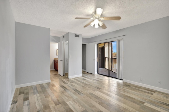 spare room featuring a ceiling fan, a textured ceiling, visible vents, baseboards, and light wood-style floors