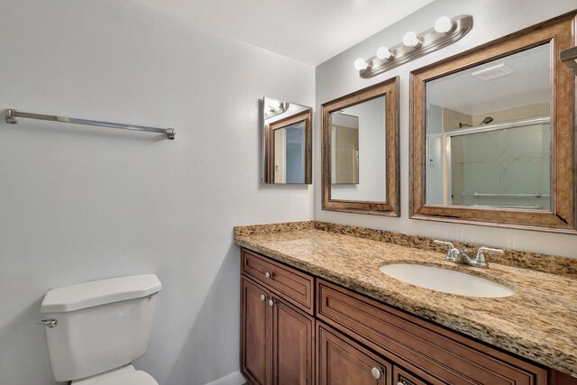 full bath with an enclosed shower, vanity, and toilet
