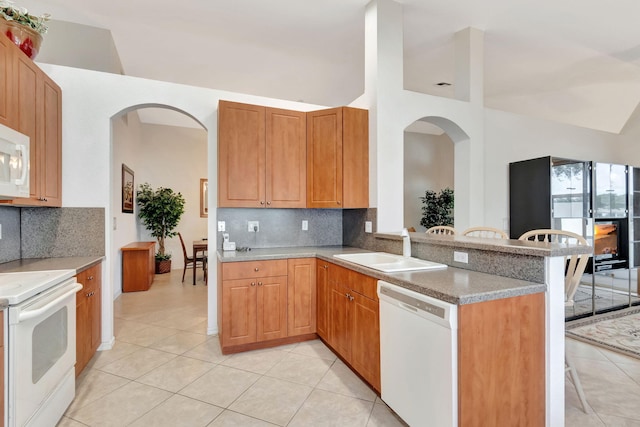 12249 Blair Ave, Boynton Beach, FL 33437 - kitchen with a peninsula, white appliances, a kitchen bar, arched walkways, and a sink