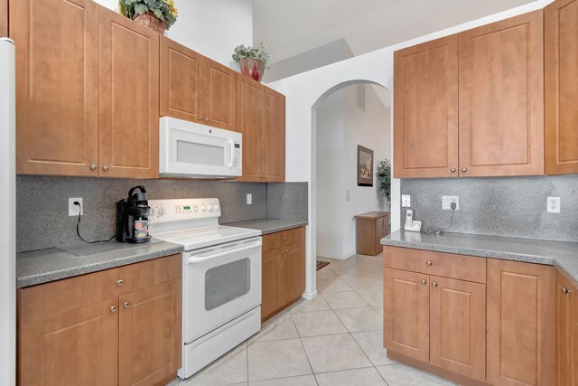 12249 Blair Ave, Boynton Beach, FL 33437 - kitchen featuring white appliances, arched walkways, light tile patterned flooring, and backsplash