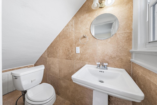 bathroom with tile walls, toilet, and a sink