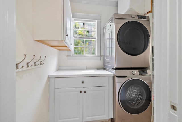washroom featuring stacked washer / dryer and cabinet space