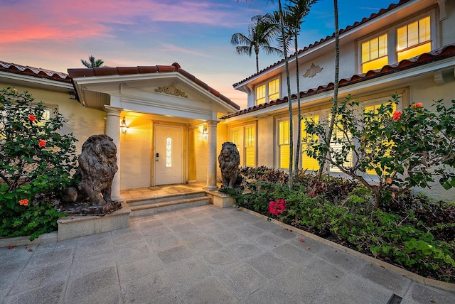 entrance to property featuring stucco siding and a tiled roof