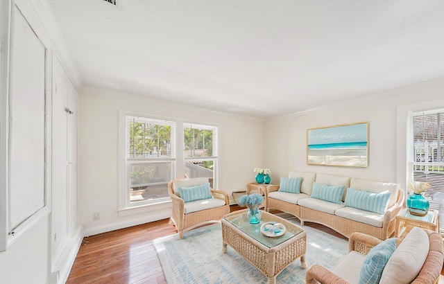 living room with crown molding, light wood-type flooring, and baseboards