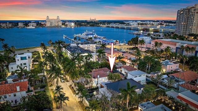 aerial view at dusk featuring a water view and a city view