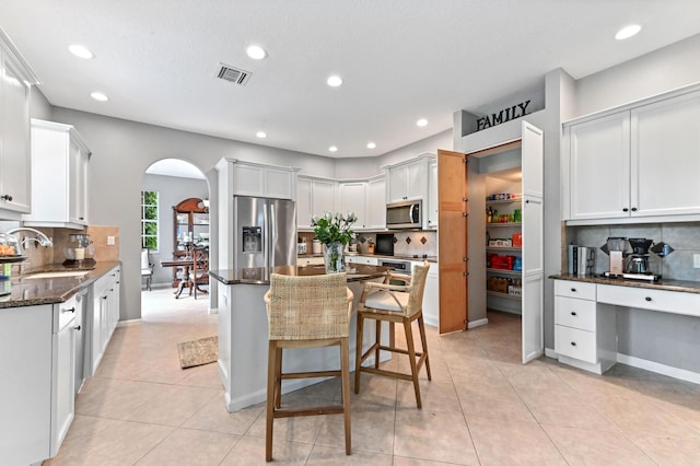 2256 Ridgewood Ct, Royal Palm Beach, FL 33411 - kitchen featuring appliances with stainless steel finishes, arched walkways, tasteful backsplash, a breakfast bar area, and recessed lighting