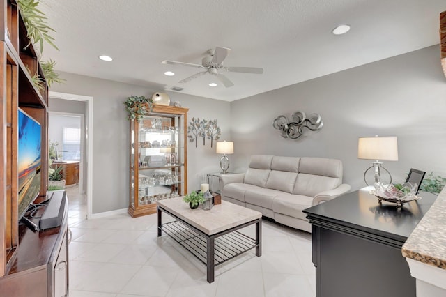 living area with ceiling fan, a textured ceiling, recessed lighting, baseboards, and light tile patterned floors