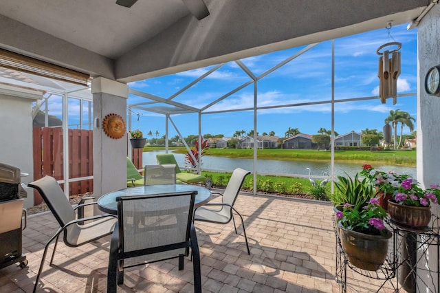 view of patio / terrace featuring a lanai, outdoor dining space, and a water view