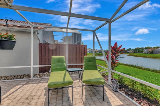 view of patio with glass enclosure and a water view
