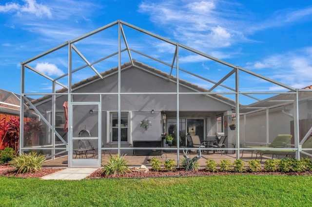 rear view of house featuring a lawn, a lanai, stucco siding, and a patio area