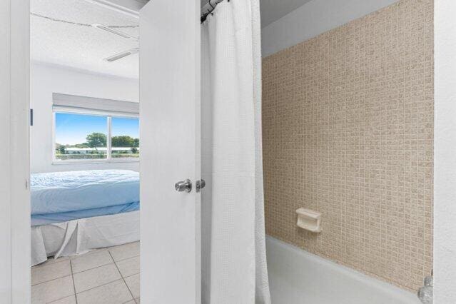 1118 Lake Ter Unit H209, Boynton Beach, FL 33426 - bedroom featuring light tile patterned floors, a water view, a ceiling fan, and a textured ceiling