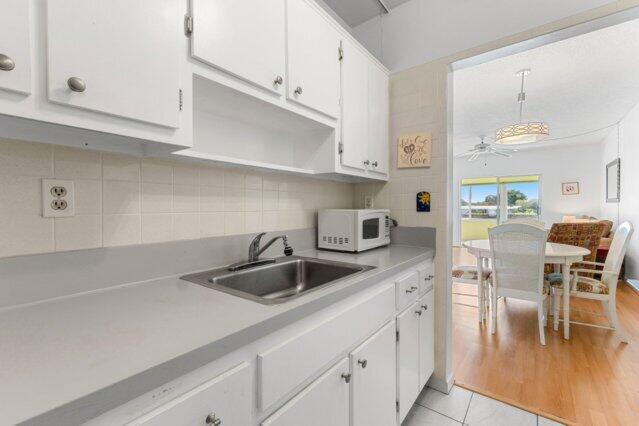 1118 Lake Ter Unit H209, Boynton Beach, FL 33426 - kitchen with open shelves, range with electric stovetop, light countertops, white cabinets, and light tile patterned floors