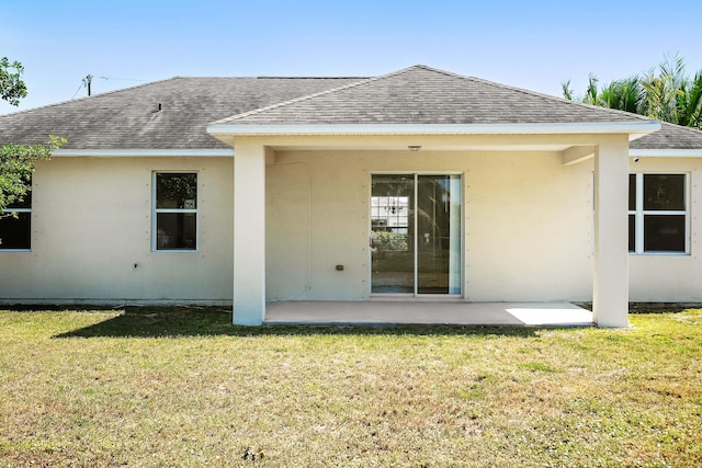 565 SW Feldman Ave N, Port Saint Lucie, FL 34953 - rear view of property featuring roof with shingles, a patio, stucco siding, and a yard