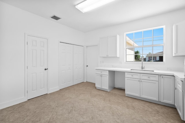 565 SW Feldman Ave N, Port Saint Lucie, FL 34953 - kitchen with light countertops, white cabinets, visible vents, and a sink