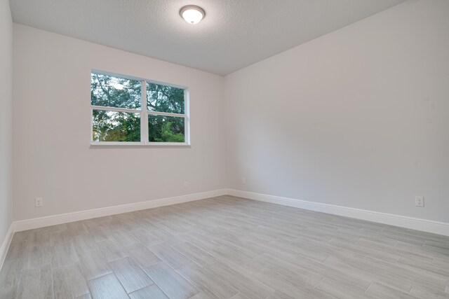 1634 SW Import Dr, Port Saint Lucie, FL 34953 - spare room featuring baseboards, a textured ceiling, and light wood-style flooring