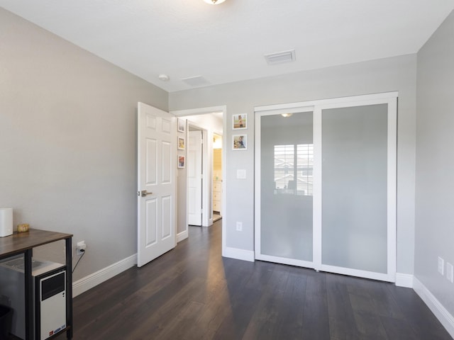 unfurnished bedroom featuring visible vents, dark wood finished floors, baseboards, and a closet