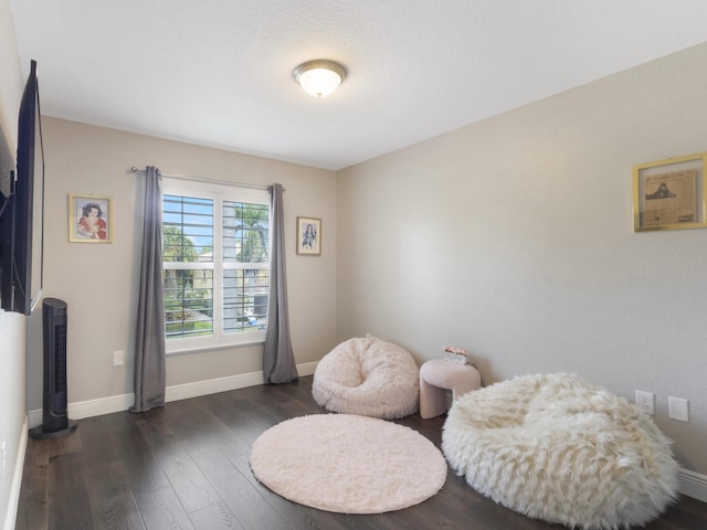 living area featuring dark wood-style flooring and baseboards
