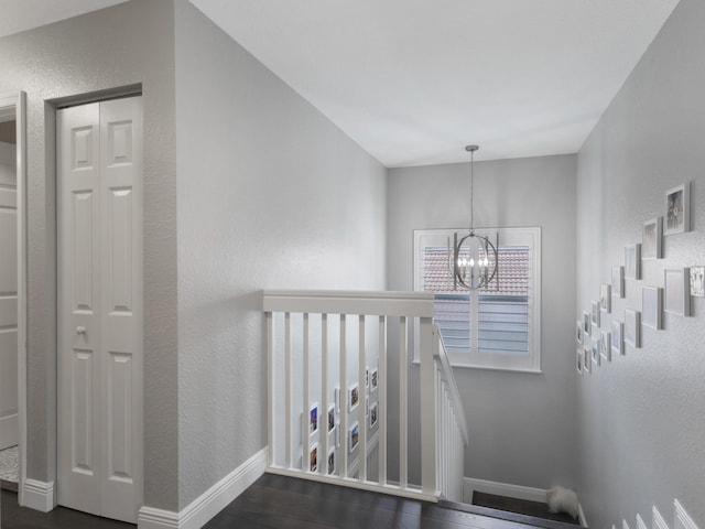 staircase featuring an inviting chandelier, baseboards, and a textured wall