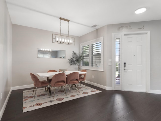 dining area featuring baseboards, a notable chandelier, wood finished floors, and visible vents
