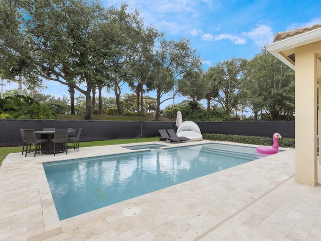 view of pool with an in ground hot tub, outdoor dining area, a patio area, a fenced in pool, and a fenced backyard