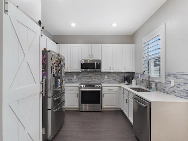 kitchen with light countertops, white cabinets, tasteful backsplash, a sink, and appliances with stainless steel finishes