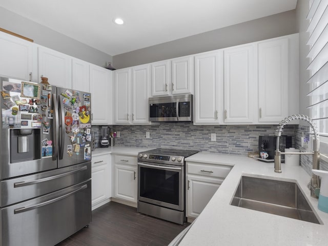 kitchen with dark wood-type flooring, white cabinetry, a sink, appliances with stainless steel finishes, and backsplash