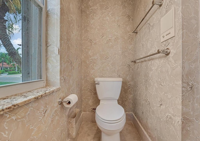 bathroom with baseboards, tile patterned floors, a wealth of natural light, and toilet