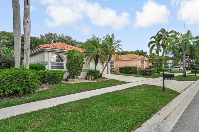 9870 Harbour Lake Cir, Boynton Beach, FL 33437 - mediterranean / spanish house with a tile roof, a front lawn, concrete driveway, an attached garage, and stucco siding